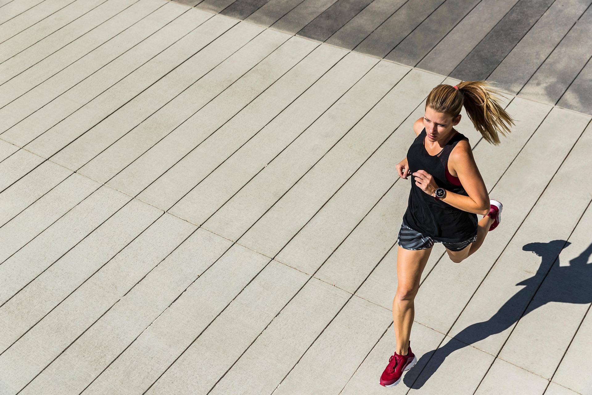 Woman running on pavement, showing the high-impact nature of running as exercise