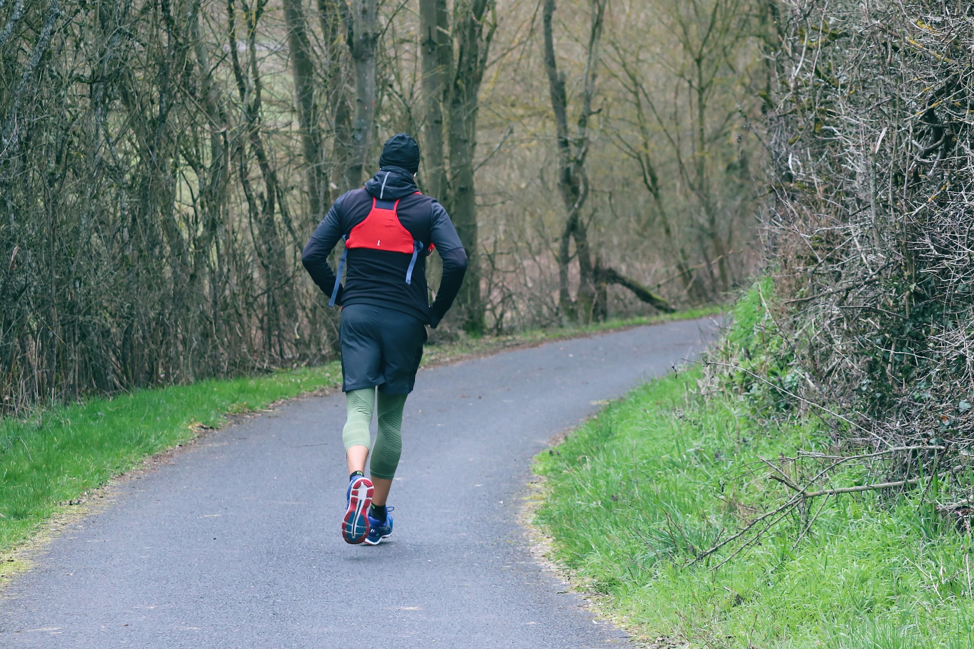Man running on a forest trail, demonstrating the running component of a ruck run workout