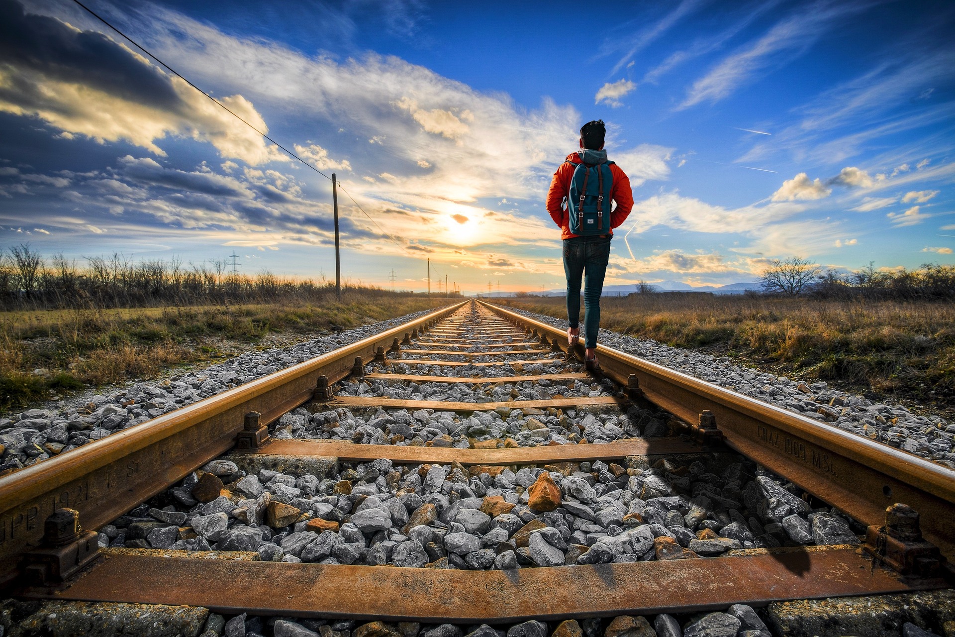 Person walking with a backpack along a path at sunset